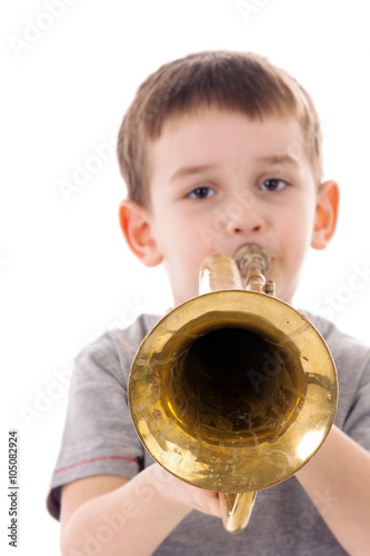 young boy blowing into a trumpet against white background