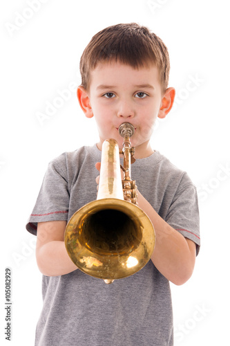 young boy blowing into a trumpet against white background