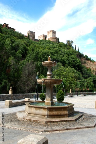 Stone fountain with the Alhambra to the rear, Granada.