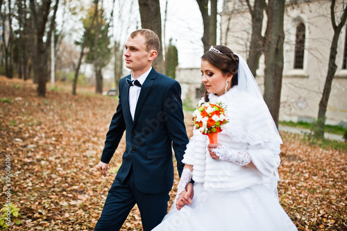 Happy wedding couple at autumn forest with fell leaves from the