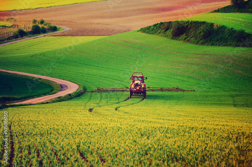 Farm machinery spraying insecticide to the green field, agricultural natural seasonal spring background, vintag retro hipster style