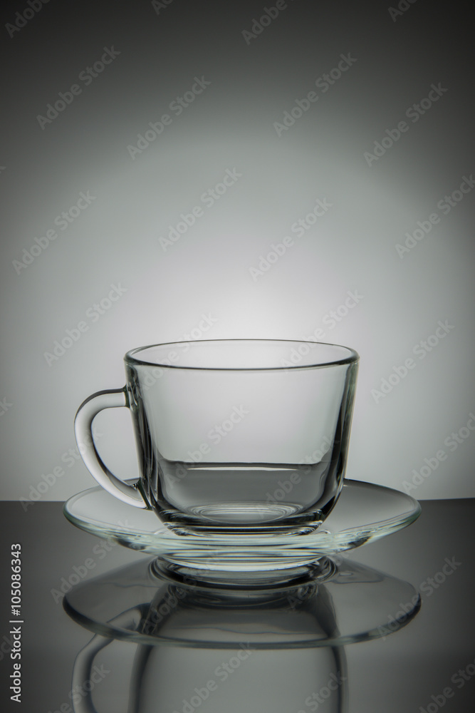 Glass empty mug of tea and saucer on a black and white backgroun Glass empty mug of tea and saucer on a black and white backgroun