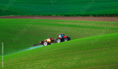 Farm machinery spraying insecticide to the green field, agricultural natural seasonal spring background