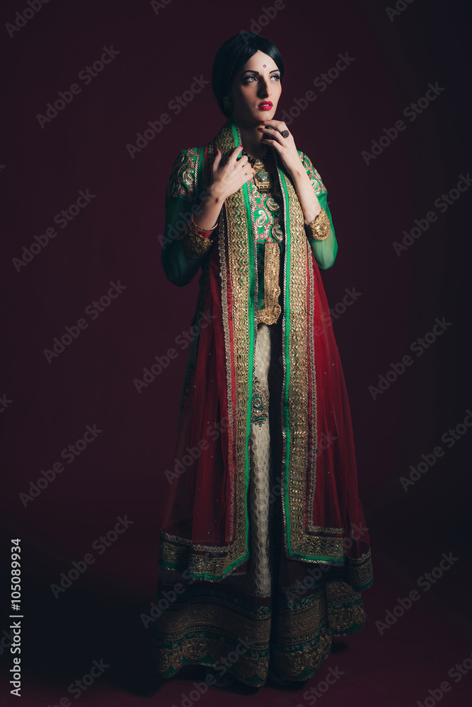 Traditional vintage Bollywood fashion girl against dark red back