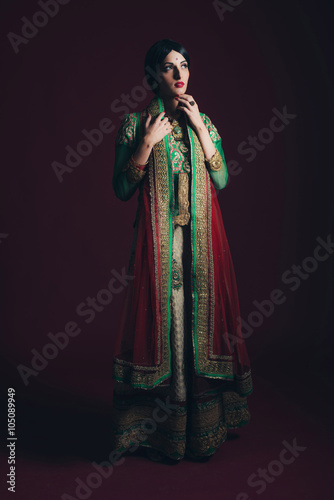 Traditional vintage Bollywood fashion girl against dark red back