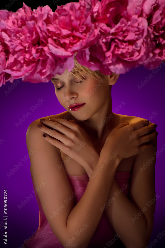 Naklejka premium Beautiful young blonde woman in big hat with pink flowers on dark blue background