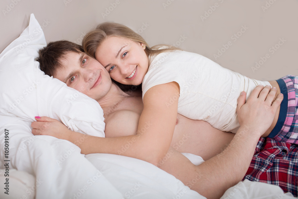 Happy young couple lying in bed and looking at camera with smiles
Happy young couple lying in bed and looking at camera with smiles