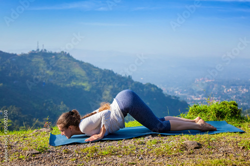 Woman doing yoga asana Ashtangasana outdoors photo