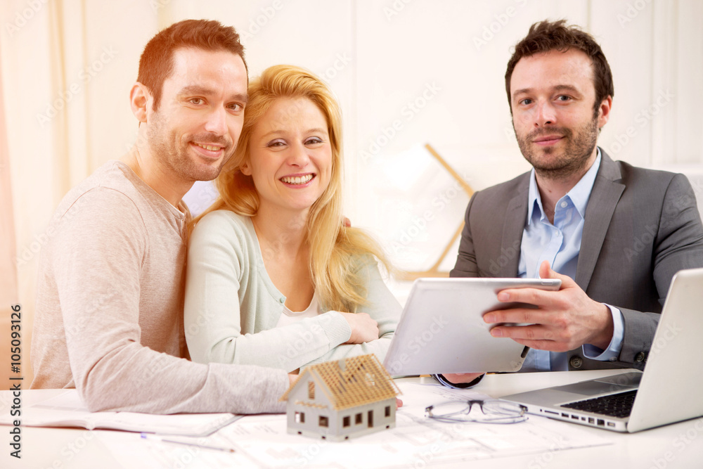 Fototapeta premium Real estate agent present project on tablet to a young couple