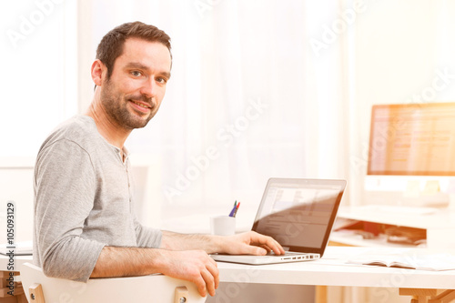 Young smiling man in front of a computer © Production Perig