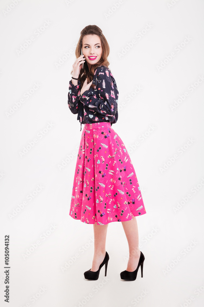 Cheerful attractive young woman standing and talking on mobile phone Cheerful attractive young woman standing and talking on mobile phone