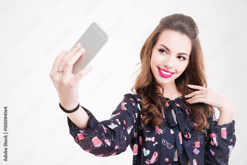 Naklejka premium Cheerful charming young woman making selfie using smartphone