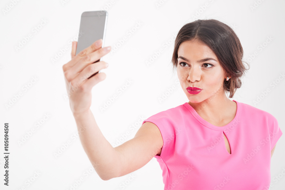 Cute woman making duck face and taking selfie using smartphone Cute woman making duck face and taking selfie using smartphone