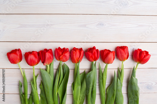 Row of tulips on wooden background with space for message. Mother's Day background. Top view
