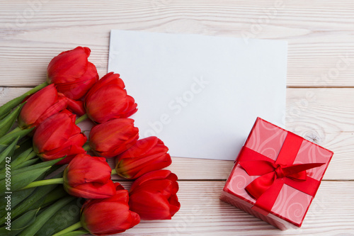 tulip bouquet, blank greeting card and gift boxes. Top view over wooden table
