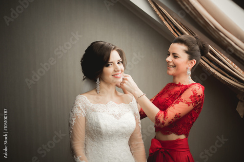 Happy buddies helps bride getting ready for her wedding day in the morning 