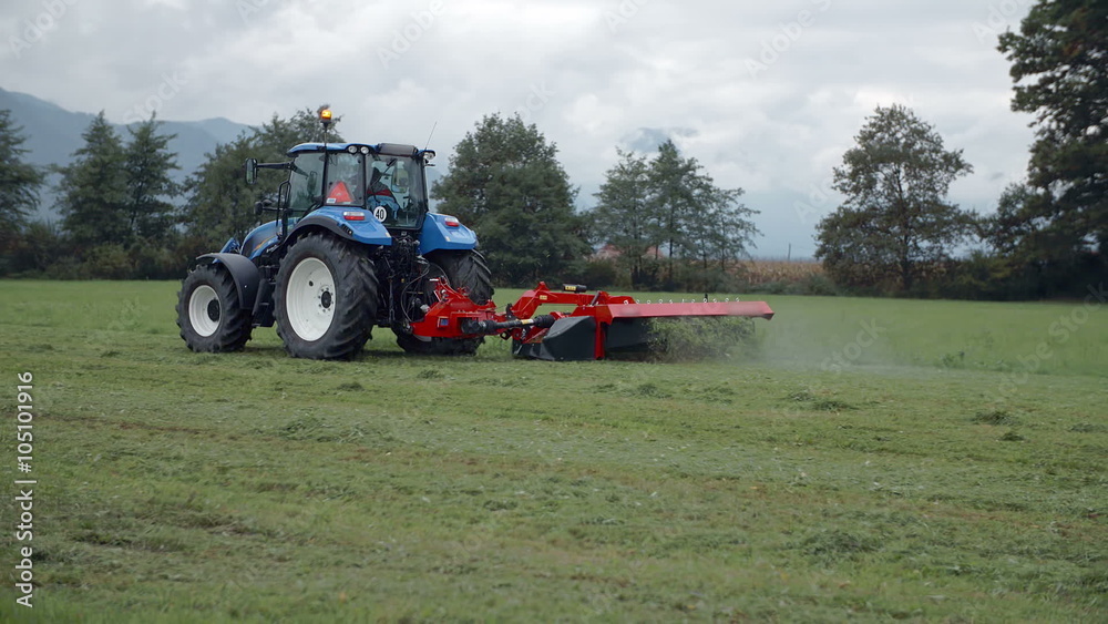 Tractor with a mowing machine is driving across the field Tractor with a mowing machine is driving across the field