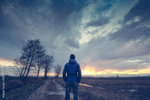  Man under a cloudy sky in the country watching the sunset 