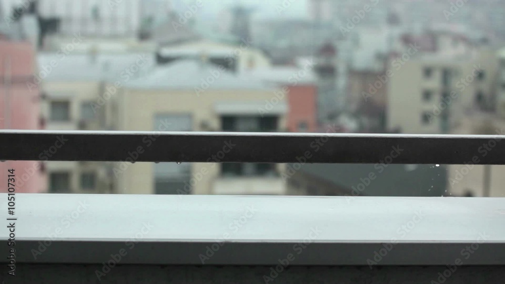 Rain falling in the city; rain drops falling onto terrace fence; close up; 