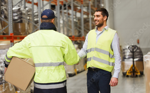 men in safety vests shaking hands at warehouse