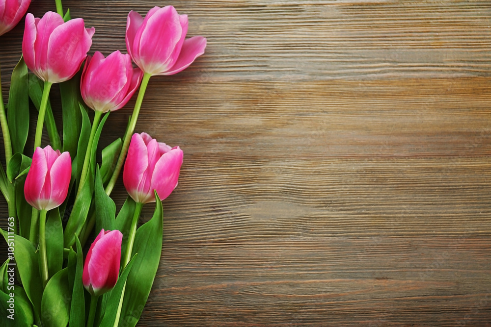 Fresh pink tulips on a wooden table, top view