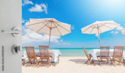 opened white door to table set and umbrella on the beach