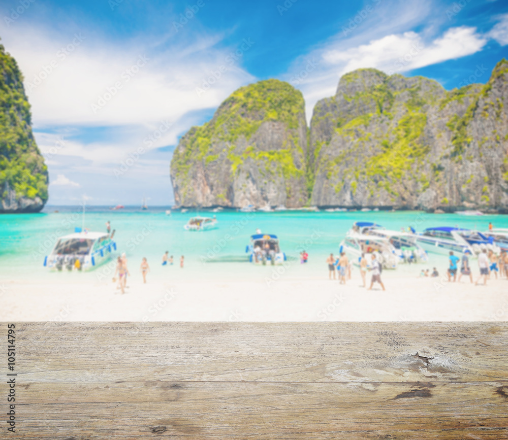 wood table top with blurred people at maya bay, phi phi leh island, thailand