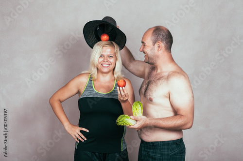 Obraz na plátně Cheerful corpulent couple with fruit and vegetable