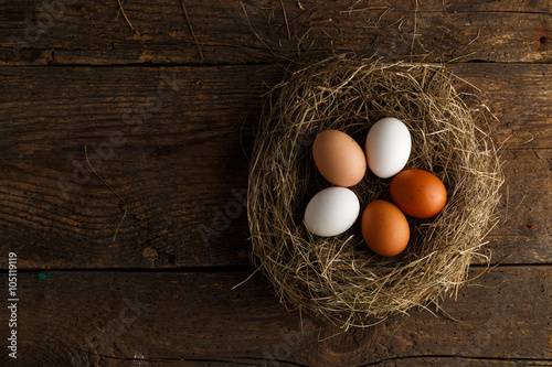 Chicken eggs in a nest on a wooden rustic background