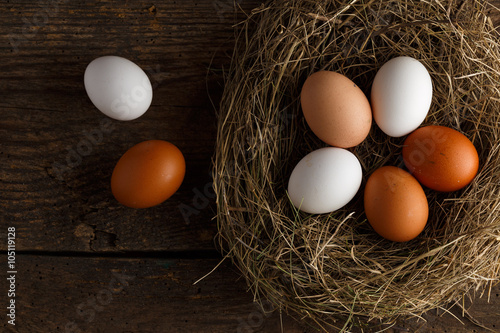 Chicken eggs in a nest on a wooden rustic background