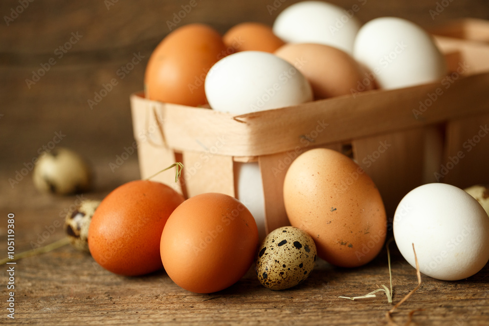 Chicken and quail eggs on a wooden rustic background