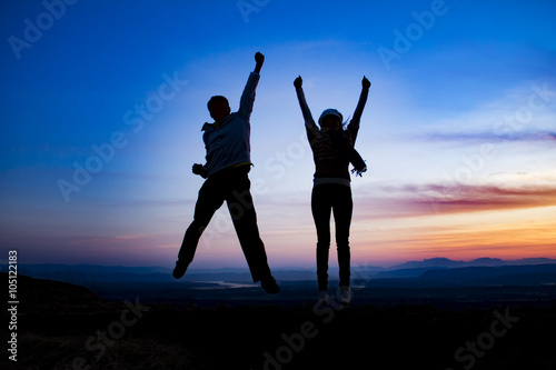 couple is jumping on top of the mountain