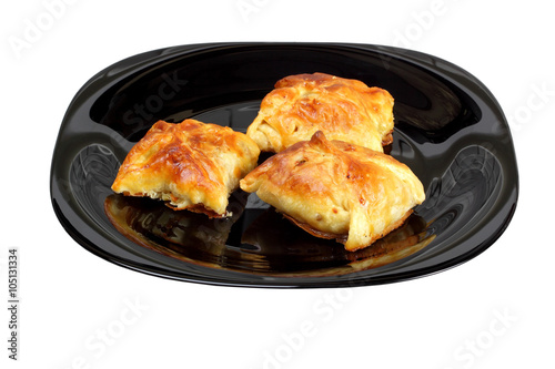 Envelopes of dough stuffed with mushrooms and chicken, baked in oven, on black plate. Isolated on white
