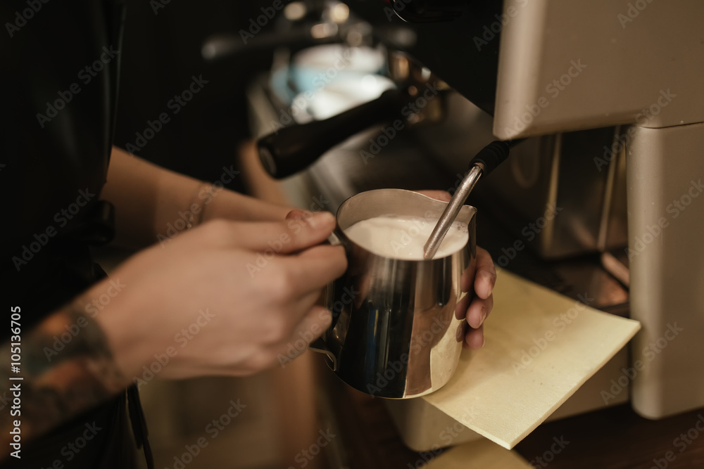 Barista steaming milk at coffee machine