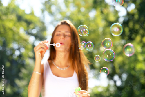 young girl inflating soap bubbles in park