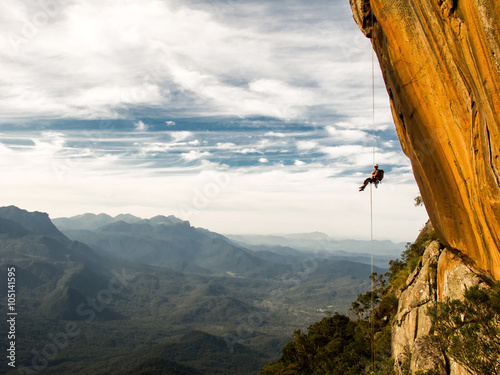 Foto Abseiling a negative yellow rock wall with mountains on backgrou
