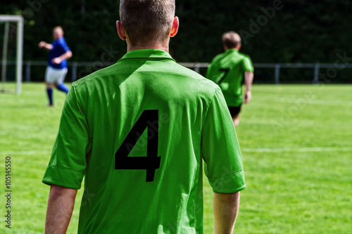 Fußballspieler auf dem Spielfeld im grünenTrikot von hinten © anko