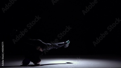 Talanted dancer in dark suit dancing breakdance, on black, shadow, slow motion photo