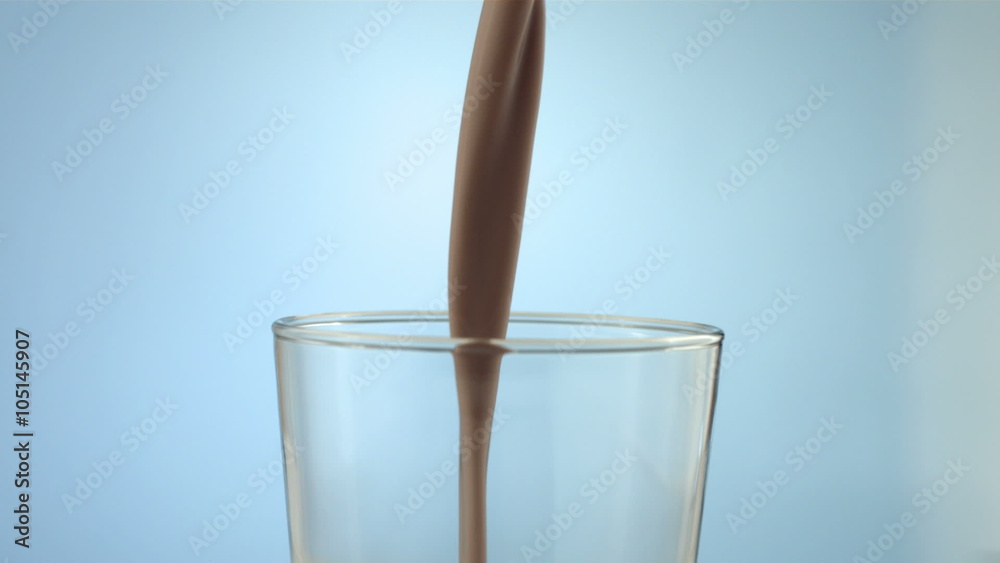 Chocolate milk pouring into glass, slow motion