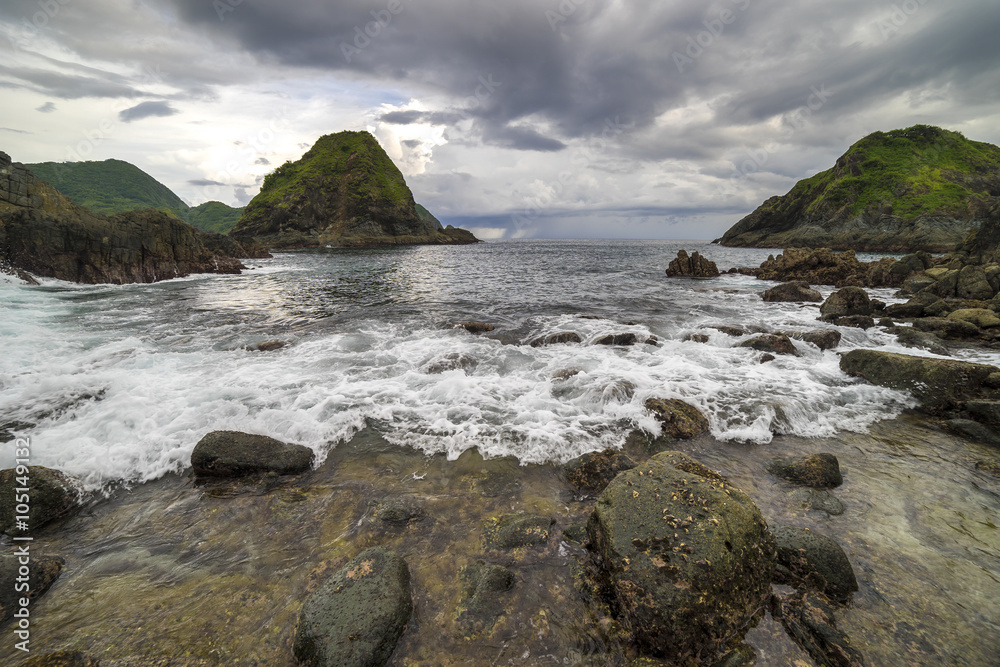 Natural rock with strong water wave and cloudy sunset background at Pantai Semeti Lombok, Indonesia.