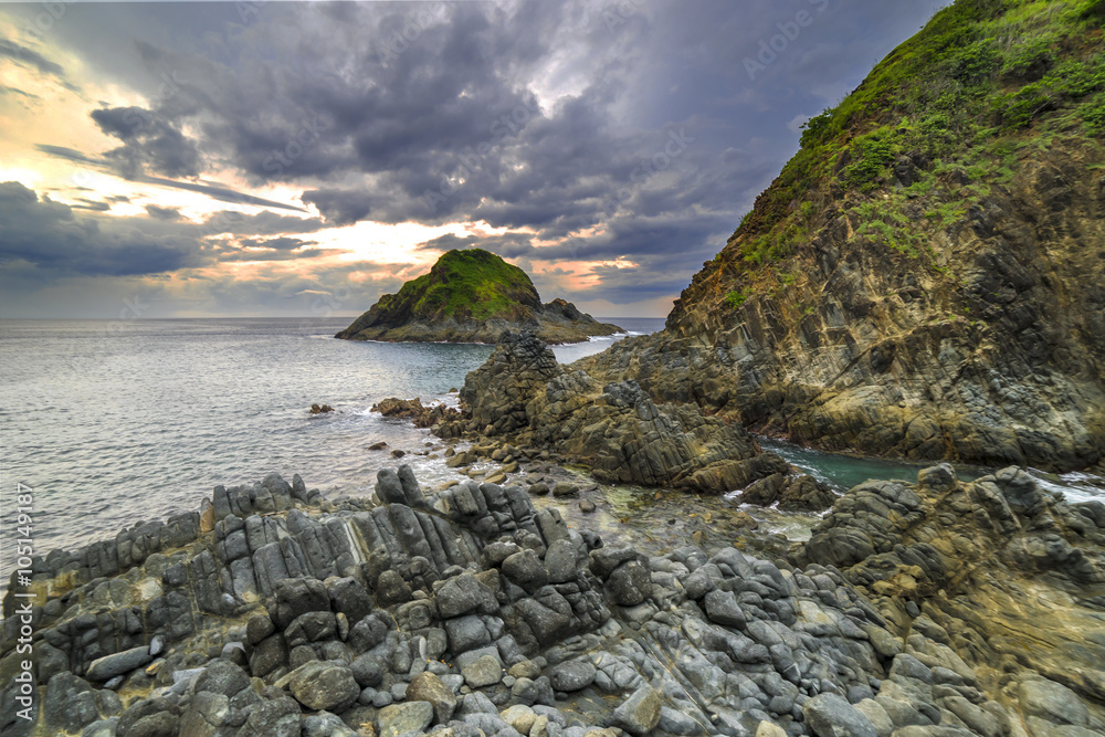 Naklejka premium Natural rock with strong water wave and cloudy sunset background at Pantai Semeti Lombok, Indonesia.