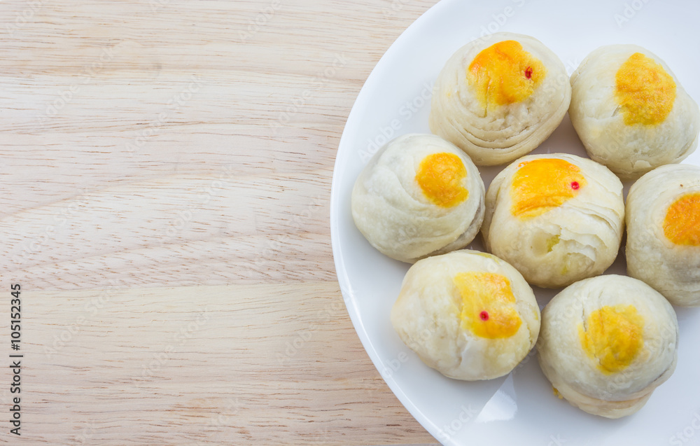 Chinese Pastry Mung Bean or Mooncake with Egg Yolk on dish and wooden table Chinese Pastry Mung Bean or Mooncake with Egg Yolk on dish and wooden table