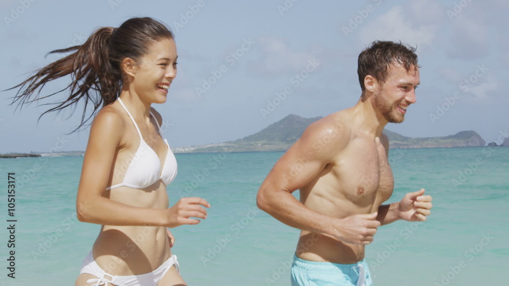 Happy couple having laughing fun on beach vacation during summer holiday. Multiracial fit couple running together in the sun. Happy couple having laughing fun on beach vacation during summer holiday. Multiracial fit couple running together in the sun.