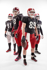 The four american football players posing with ball on white background