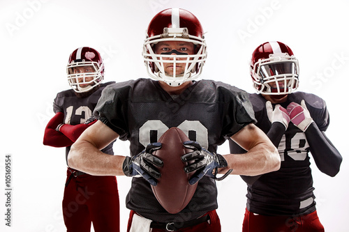 The three american football players posing with ball on white background