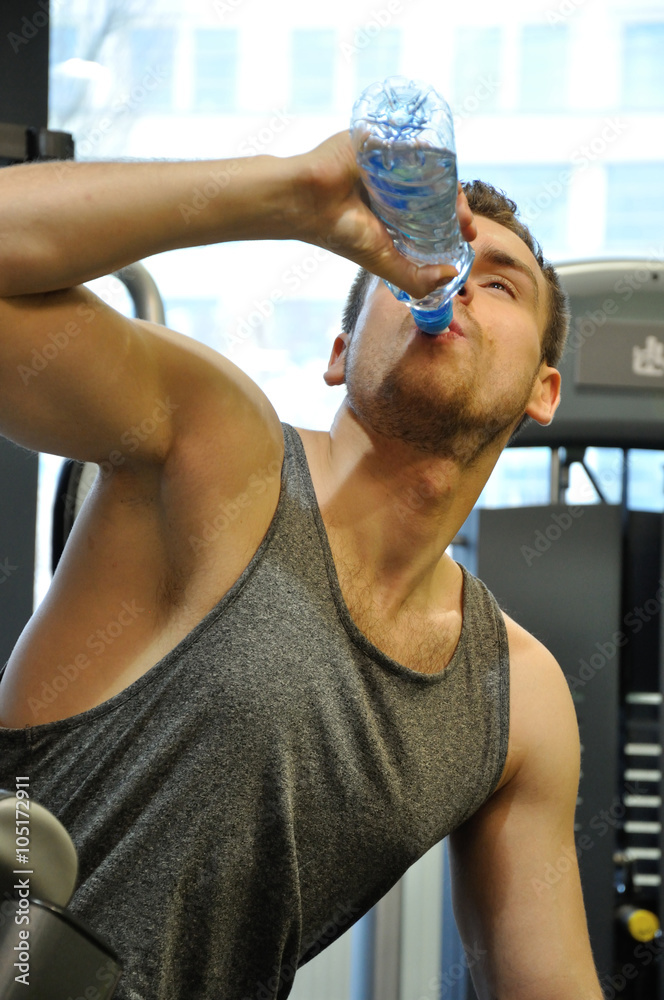 Fototapeta premium Mężczyzna na siłowni pijący wodę.