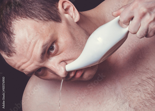 Close up portrait of a man cleaning his nose using white ceramic