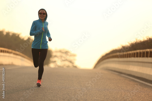 young woman runner athlete running at sunrise city road