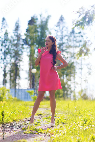 Young pretty woman poses showing dress summer outdoors in sunset