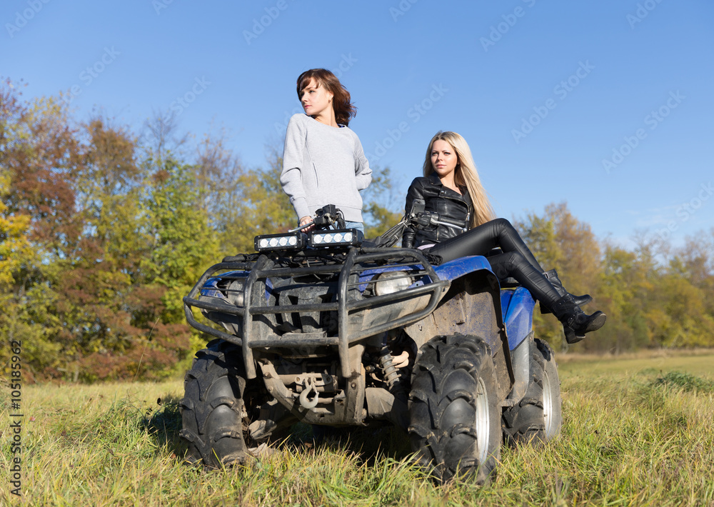 Fototapeta premium Two elegant women riding extreme quadrocycle ATV